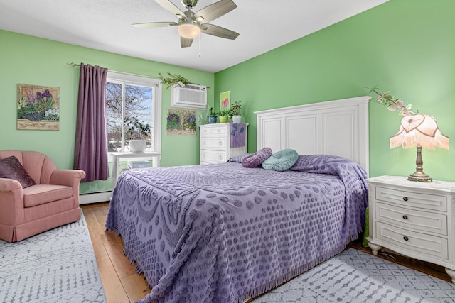 bedroom featuring a baseboard radiator, a wall mounted AC, ceiling fan, and light wood-type flooring