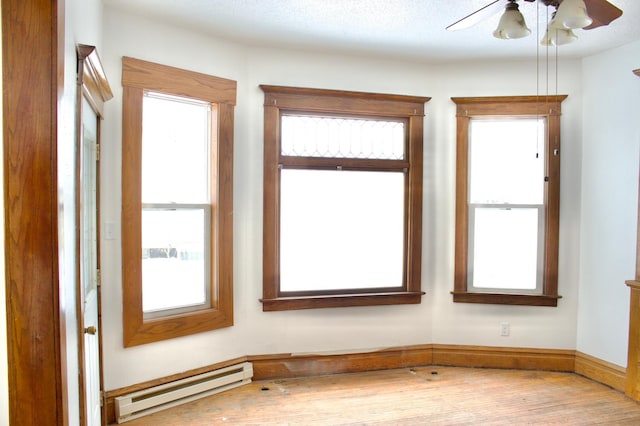 spare room featuring ceiling fan, hardwood / wood-style flooring, and a baseboard heating unit