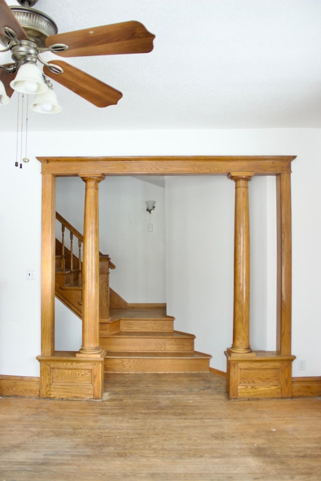 stairway with hardwood / wood-style flooring and ceiling fan