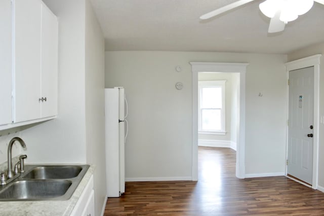 kitchen with sink, dark hardwood / wood-style floors, ceiling fan, white fridge, and white cabinetry