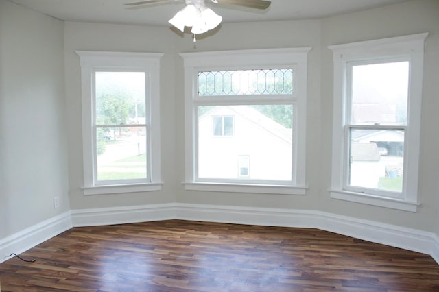 empty room with ceiling fan, a healthy amount of sunlight, and dark hardwood / wood-style flooring