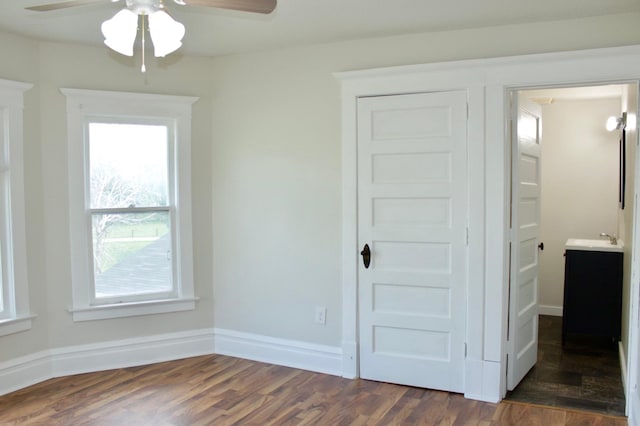 unfurnished bedroom with dark hardwood / wood-style floors, ceiling fan, sink, and multiple windows