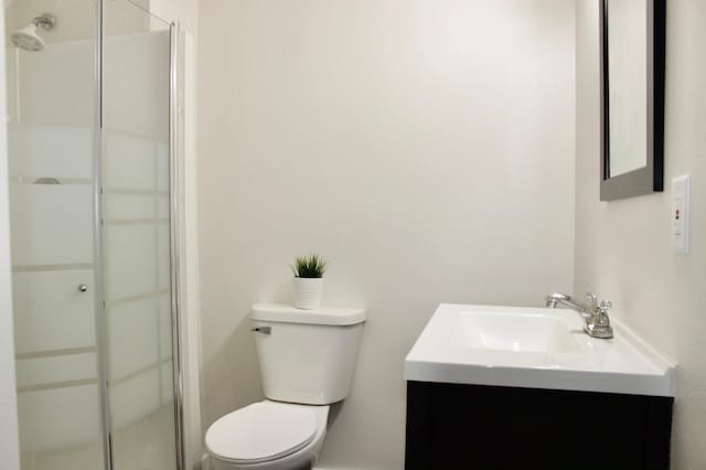 bathroom featuring vanity, toilet, and a shower with door