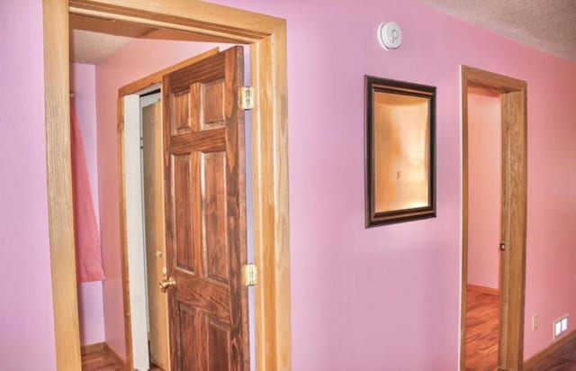 hall with hardwood / wood-style floors and a textured ceiling