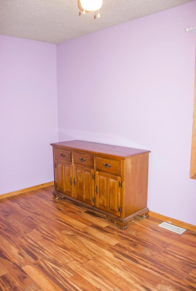 empty room with a textured ceiling and light hardwood / wood-style flooring