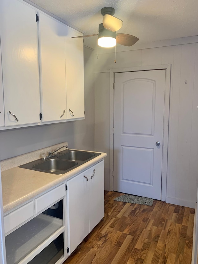 kitchen with a textured ceiling, dark hardwood / wood-style flooring, white cabinetry, and sink