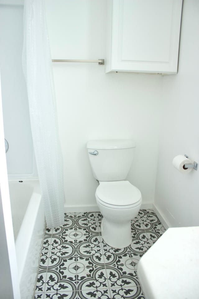 bathroom with tile patterned flooring, shower / bath combination with curtain, and toilet