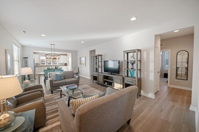 living room with light hardwood / wood-style floors and an inviting chandelier