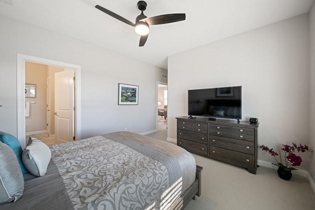 bedroom featuring ceiling fan, light colored carpet, and ensuite bathroom