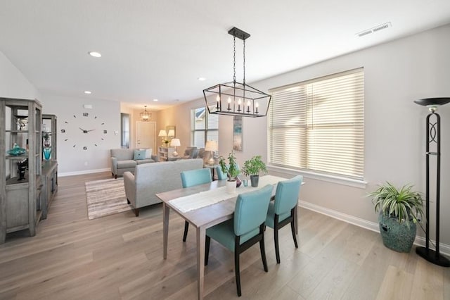 dining space with a notable chandelier and light hardwood / wood-style flooring