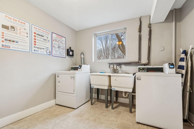 clothes washing area featuring sink, washing machine and dryer, and a textured ceiling