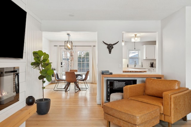 living room featuring light hardwood / wood-style flooring, a textured ceiling, and a notable chandelier