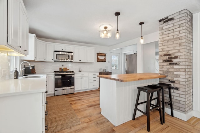 kitchen featuring a breakfast bar, white cabinets, sink, appliances with stainless steel finishes, and light hardwood / wood-style floors