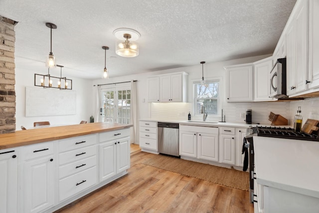 kitchen with wood counters, white cabinetry, plenty of natural light, and appliances with stainless steel finishes