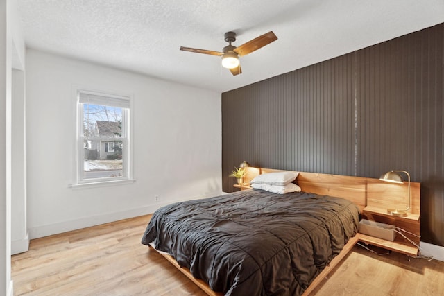 bedroom featuring ceiling fan, light hardwood / wood-style floors, and a textured ceiling