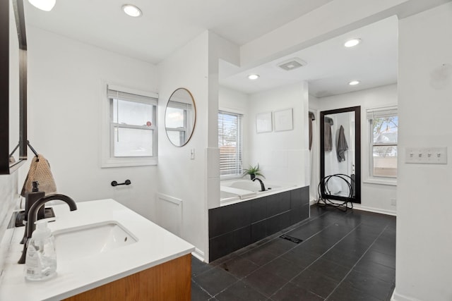 bathroom featuring tiled tub, plenty of natural light, vanity, and tile patterned flooring