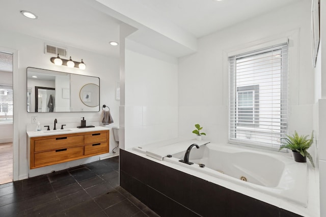 bathroom with tile patterned flooring, vanity, and tiled bath