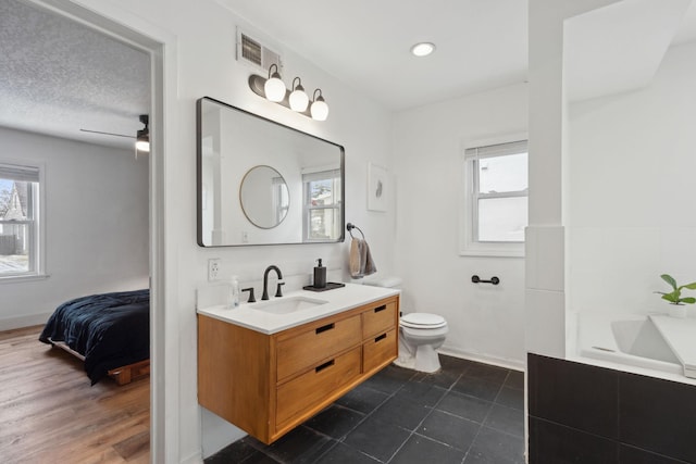 bathroom with vanity, a textured ceiling, ceiling fan, wood-type flooring, and toilet