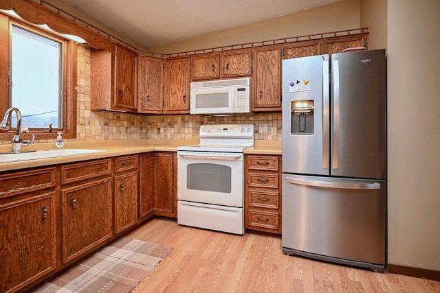 kitchen with white appliances, light hardwood / wood-style floors, backsplash, and sink