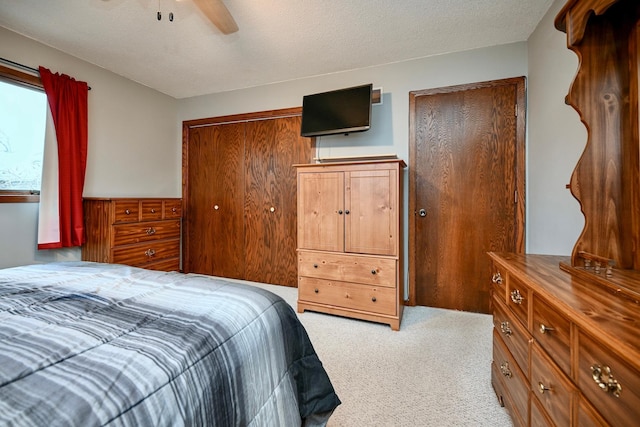 carpeted bedroom featuring ceiling fan and a textured ceiling