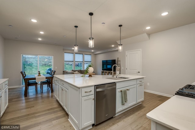 kitchen with light countertops, a kitchen island with sink, white cabinets, a sink, and dishwasher