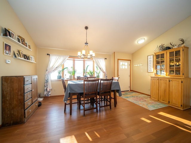 dining area featuring light hardwood / wood-style floors, an inviting chandelier, and vaulted ceiling