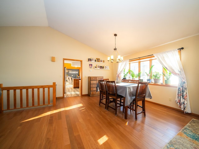 dining room featuring a chandelier, wood-type flooring, and vaulted ceiling