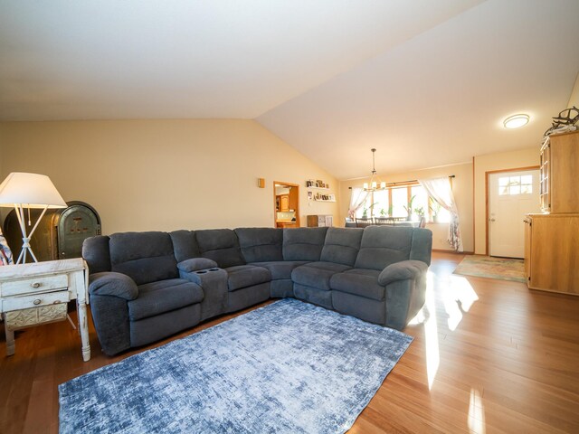 living room featuring hardwood / wood-style floors, an inviting chandelier, and vaulted ceiling