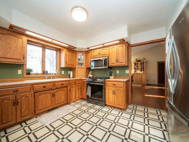 kitchen with stainless steel appliances, lofted ceiling, and light hardwood / wood-style floors