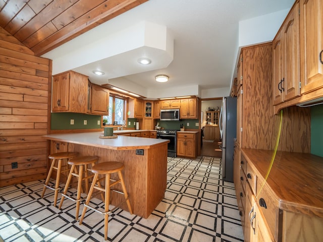 kitchen featuring wooden ceiling, stainless steel appliances, kitchen peninsula, vaulted ceiling, and a breakfast bar area