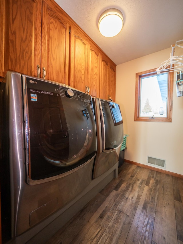 laundry room featuring washer and dryer, dark hardwood / wood-style floors, and cabinets