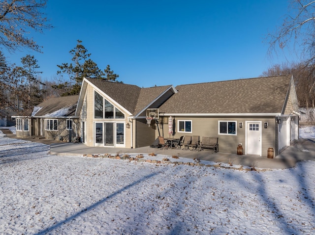 snow covered back of property with a patio area