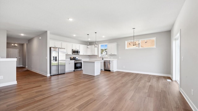 kitchen featuring a center island, stainless steel appliances, light hardwood / wood-style flooring, decorative light fixtures, and white cabinets