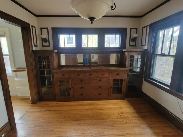 unfurnished dining area with light hardwood / wood-style flooring, a wealth of natural light, and crown molding