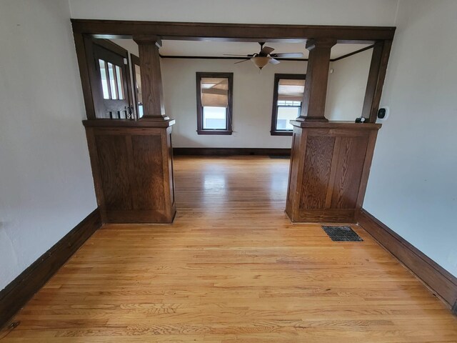 hall with light wood-type flooring and decorative columns