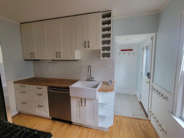 kitchen featuring stainless steel dishwasher, butcher block countertops, crown molding, white cabinets, and light wood-type flooring