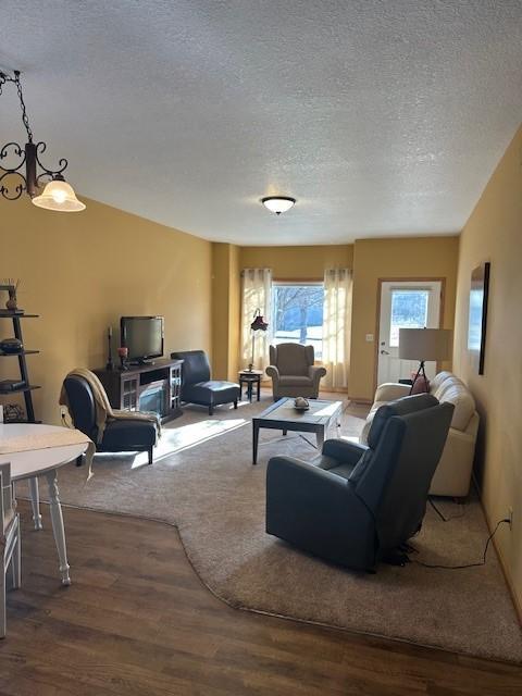 living room with hardwood / wood-style floors, a textured ceiling, and a notable chandelier