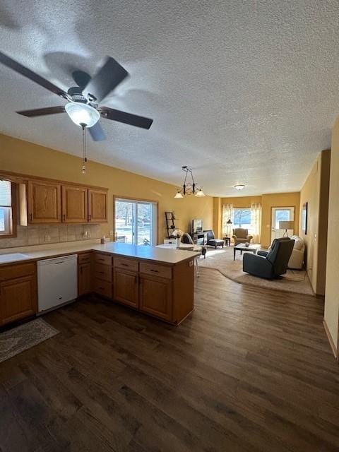 kitchen with dishwasher, dark hardwood / wood-style floors, kitchen peninsula, and decorative light fixtures