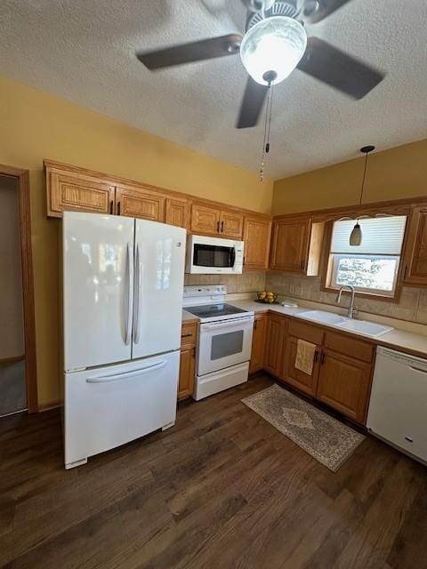 kitchen featuring white appliances, backsplash, sink, dark hardwood / wood-style floors, and decorative light fixtures