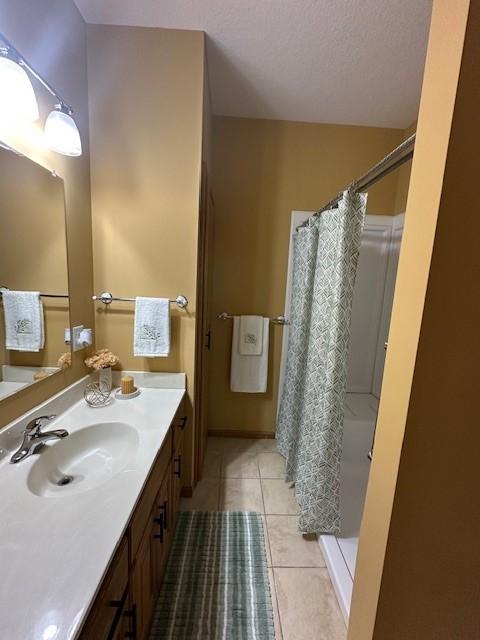 bathroom featuring a textured ceiling, vanity, tile patterned floors, and walk in shower