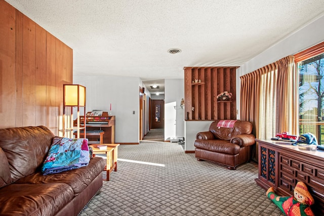 living room featuring wood walls, carpet floors, and a textured ceiling