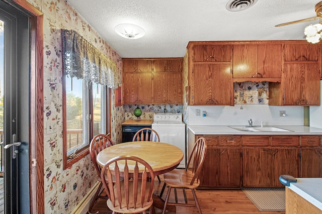 kitchen with sink, light hardwood / wood-style flooring, ceiling fan, a textured ceiling, and washer / dryer