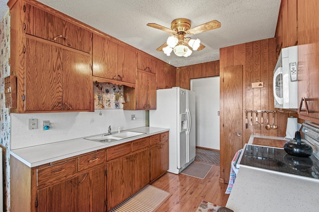 kitchen with white appliances, sink, light hardwood / wood-style flooring, ceiling fan, and a textured ceiling