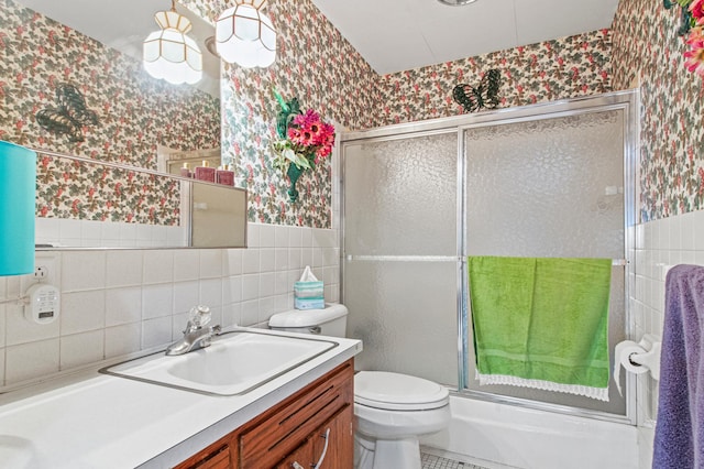 full bathroom with toilet, combined bath / shower with glass door, tile walls, and vanity