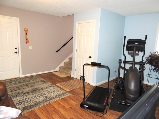 exercise area featuring wood-type flooring and a textured ceiling