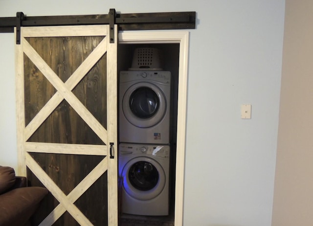 laundry room with stacked washer / drying machine, laundry area, and a barn door