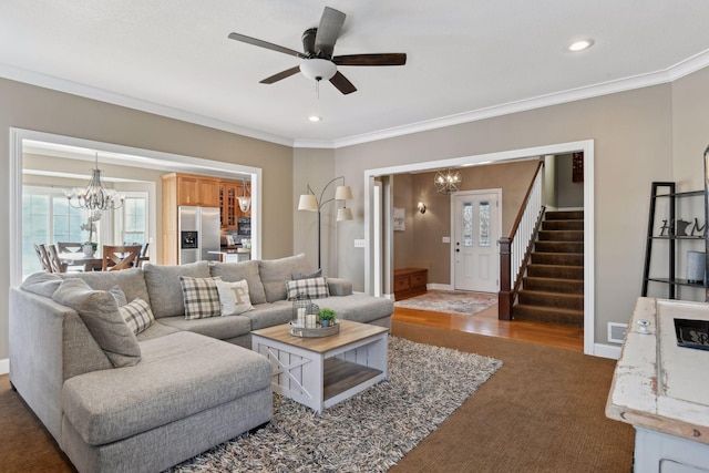 living room with ceiling fan with notable chandelier, ornamental molding, and dark hardwood / wood-style flooring