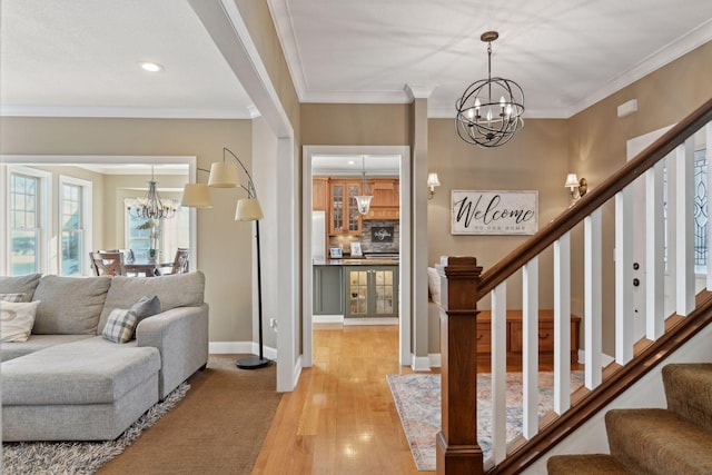 entryway featuring ornamental molding, light wood-type flooring, and an inviting chandelier