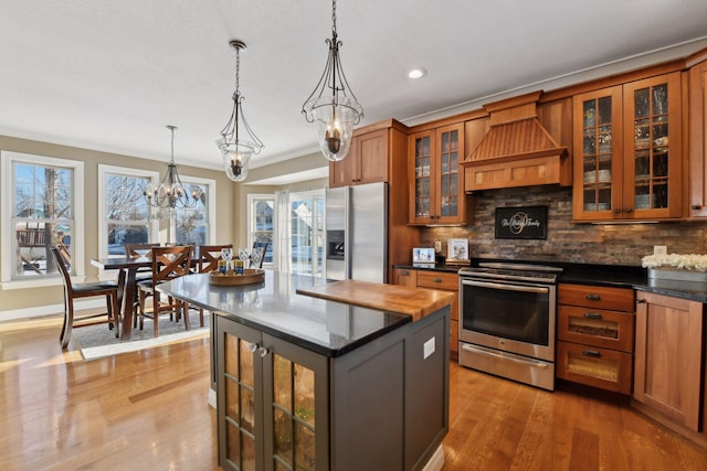 kitchen with appliances with stainless steel finishes, a center island, decorative light fixtures, and premium range hood