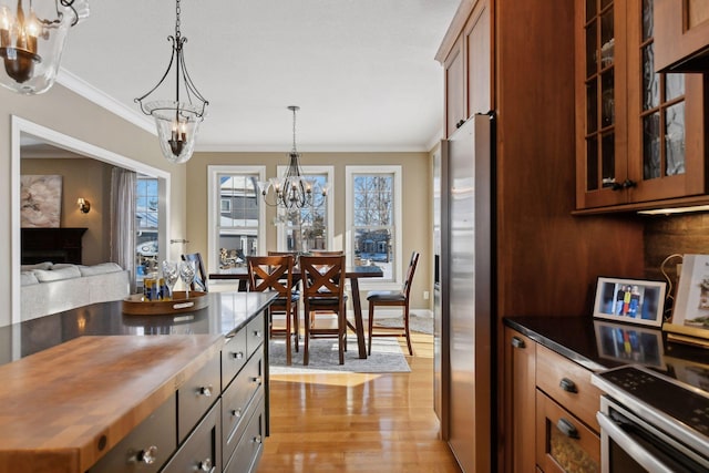 kitchen featuring a chandelier, decorative light fixtures, light wood-type flooring, stainless steel refrigerator, and ornamental molding